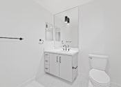 Thumbnail 119 of 119 - A white bathroom with a toilet, sink, and mirror.