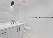 Thumbnail 52 of 119 - A white bathroom with a toilet, sink, and mirror.