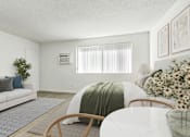 Thumbnail 3 of 73 - A living room with a white couch, a round wooden table, and a white bed with a green blanket.