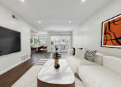 Thumbnail 16 of 95 - A modern living room with a white sofa and a large TV on the wall.