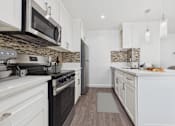 Thumbnail 2 of 91 - A kitchen with a black stove top oven and white cabinets.