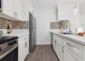 Thumbnail 1 of 91 - A kitchen with a black stove top oven and white cabinets.