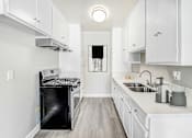 Thumbnail 19 of 50 - an all white kitchen with white cabinets and a black oven