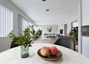 Thumbnail 5 of 60 - A table with a vase of greenery and a plate of fruit sits in a modern kitchen.