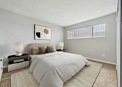 Thumbnail 7 of 60 - A bedroom with a large bed and a nightstand with a lamp.