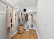 Thumbnail 9 of 60 - A white closet with clothes hanging and a basket on the floor.