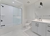 Thumbnail 95 of 119 - A white bathroom with a walk in shower and a toilet.