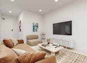 Thumbnail 5 of 20 - A living room with a brown couch, a white coffee table, and a flat screen TV mounted on the wall.