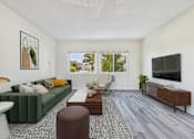 Thumbnail 2 of 36 - A living room with a green couch, a coffee table, a chair, a lamp, a plant, and a flat-screen TV mounted on the wall.