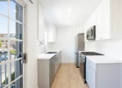 Thumbnail 17 of 32 - a white kitchen with stainless steel appliances and white cabinets
