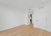 Thumbnail 41 of 119 - A white room with a wooden floor and a white door.