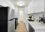 Thumbnail 3 of 44 - A kitchen with white cabinets and a black refrigerator.