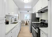 Thumbnail 2 of 44 - A kitchen with white cabinets and a black stove top oven.