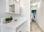 Thumbnail 9 of 24 - a bathroom with a sink and a mirror and a hallway to a bedroom