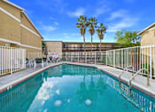 Thumbnail 34 of 35 - A pool surrounded by a metal fence and palm trees.