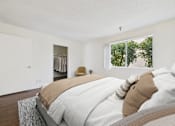 Thumbnail 9 of 35 - A bedroom with a large bed and a window overlooking trees.