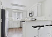 Thumbnail 2 of 45 - A kitchen with white cabinets and a black fridge.