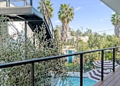 Thumbnail 104 of 119 - A pool with a striped umbrella and a balcony with a railing.