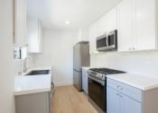 Thumbnail 19 of 32 - a kitchen with white cabinets and a stainless steel stove