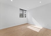 Thumbnail 51 of 119 - A room with wooden flooring and a window showing a building outside.