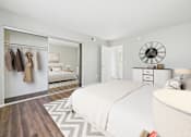 Thumbnail 5 of 41 - A bedroom with a large bed and a wardrobe with clothes hanging.