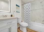 Thumbnail 22 of 45 - A white toilet sits in a bathroom with a patterned shower curtain.