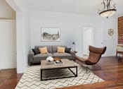 Thumbnail 22 of 61 - A living room with a grey couch, a brown chair, and a coffee table.