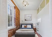 Thumbnail 23 of 61 - A bedroom with a brick wall and a bed with a blue headboard.
