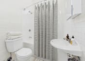 Thumbnail 25 of 61 - A white bathroom with a toilet, sink, and shower curtain.