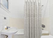 Thumbnail 16 of 61 - A white bathroom with a shower curtain and a white sink.
