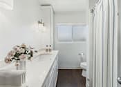 Thumbnail 5 of 29 - A white bathroom with a toilet, sink, and striped shower curtain.