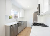 Thumbnail 23 of 32 - a renovated kitchen with white cabinets and stainless steel appliances