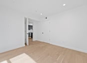Thumbnail 56 of 119 - A room with a wooden floor and white walls with a doorway leading to another room.