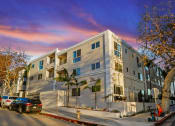 Thumbnail 13 of 66 - an apartment building on a city street with parked cars
