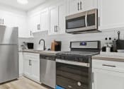Thumbnail 1 of 66 - a white kitchen with stainless steel appliances and white cabinets