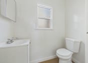 Thumbnail 9 of 20 - A white toilet sits next to a white sink in a small bathroom.