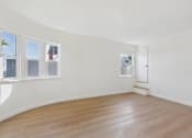 Thumbnail 6 of 20 - Empty room with wooden floor and white walls.