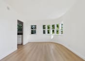 Thumbnail 3 of 20 - A white room with a wooden floor and a window with a view of trees.
