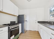 Thumbnail 1 of 20 - A kitchen with white cabinets and a black stove top oven.