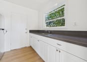 Thumbnail 2 of 20 - A kitchen with white cabinets and a window.