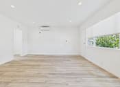 Thumbnail 6 of 30 - A spacious room with wooden flooring and white walls.