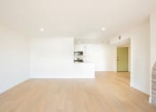 Thumbnail 15 of 28 - a living room and kitchen with white walls and wood floors