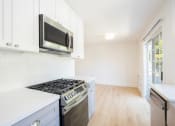Thumbnail 24 of 32 - a kitchen with white cabinets and a stove and a microwave