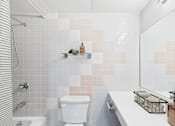 Thumbnail 11 of 123 - A white toilet sits in a bathroom with a shower and a sink.