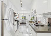 Thumbnail 6 of 19 - A kitchen with a stainless steel refrigerator and white cabinets.