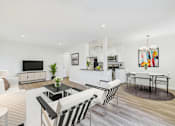 Thumbnail 9 of 19 - A modern living room with a television, a coffee table, and a dining table.