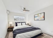 Thumbnail 8 of 19 - A bedroom with a bed, nightstands, and a ceiling fan.