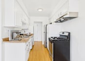Thumbnail 1 of 19 - A kitchen with white cabinets and a black stove top oven.