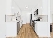 Thumbnail 11 of 32 - A kitchen with white cabinets and black appliances.