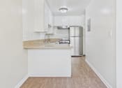 Thumbnail 23 of 51 - A kitchen with white cabinets and a wooden floor.
